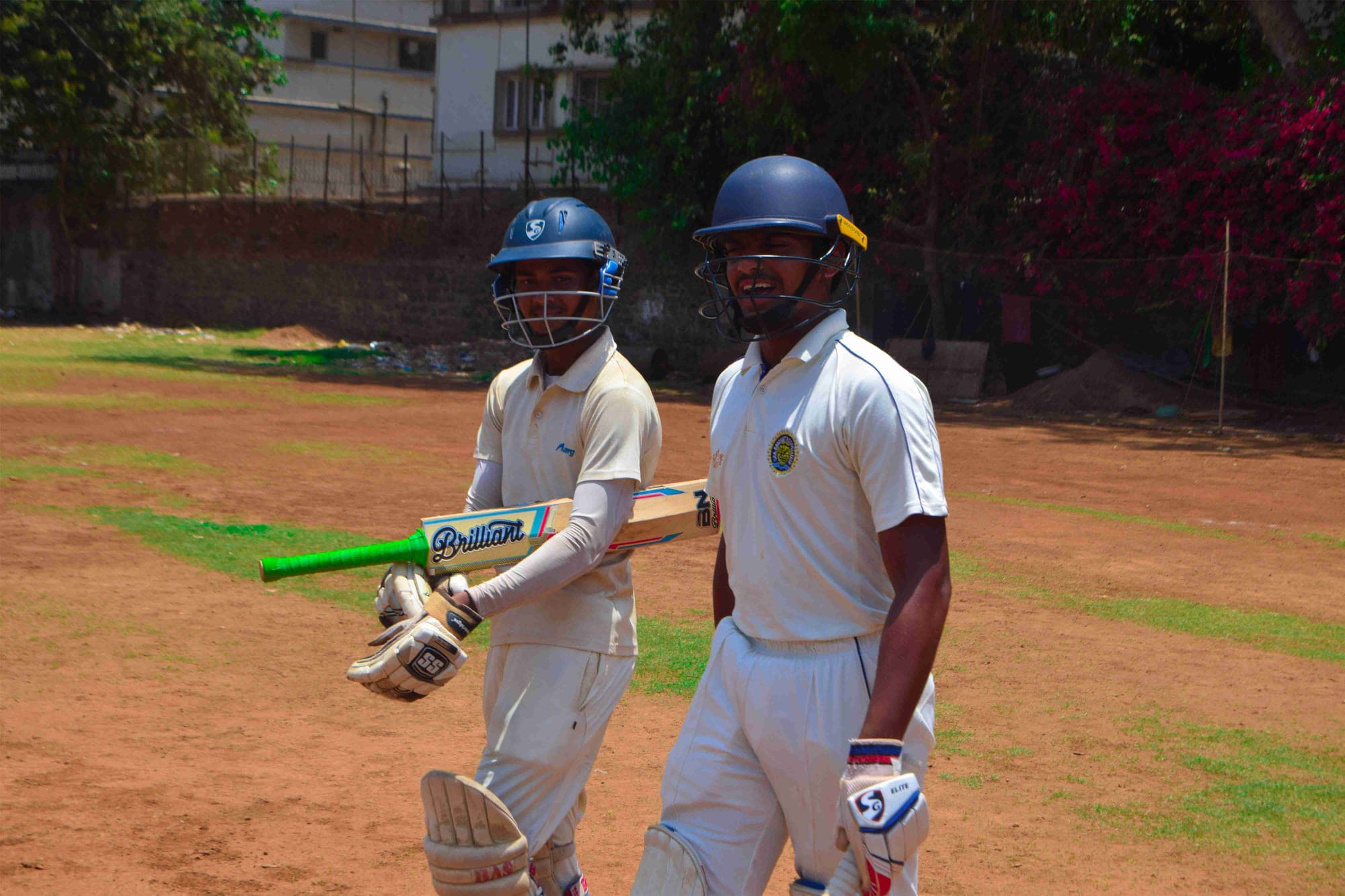 Two padded-up batsmen walking out to bat