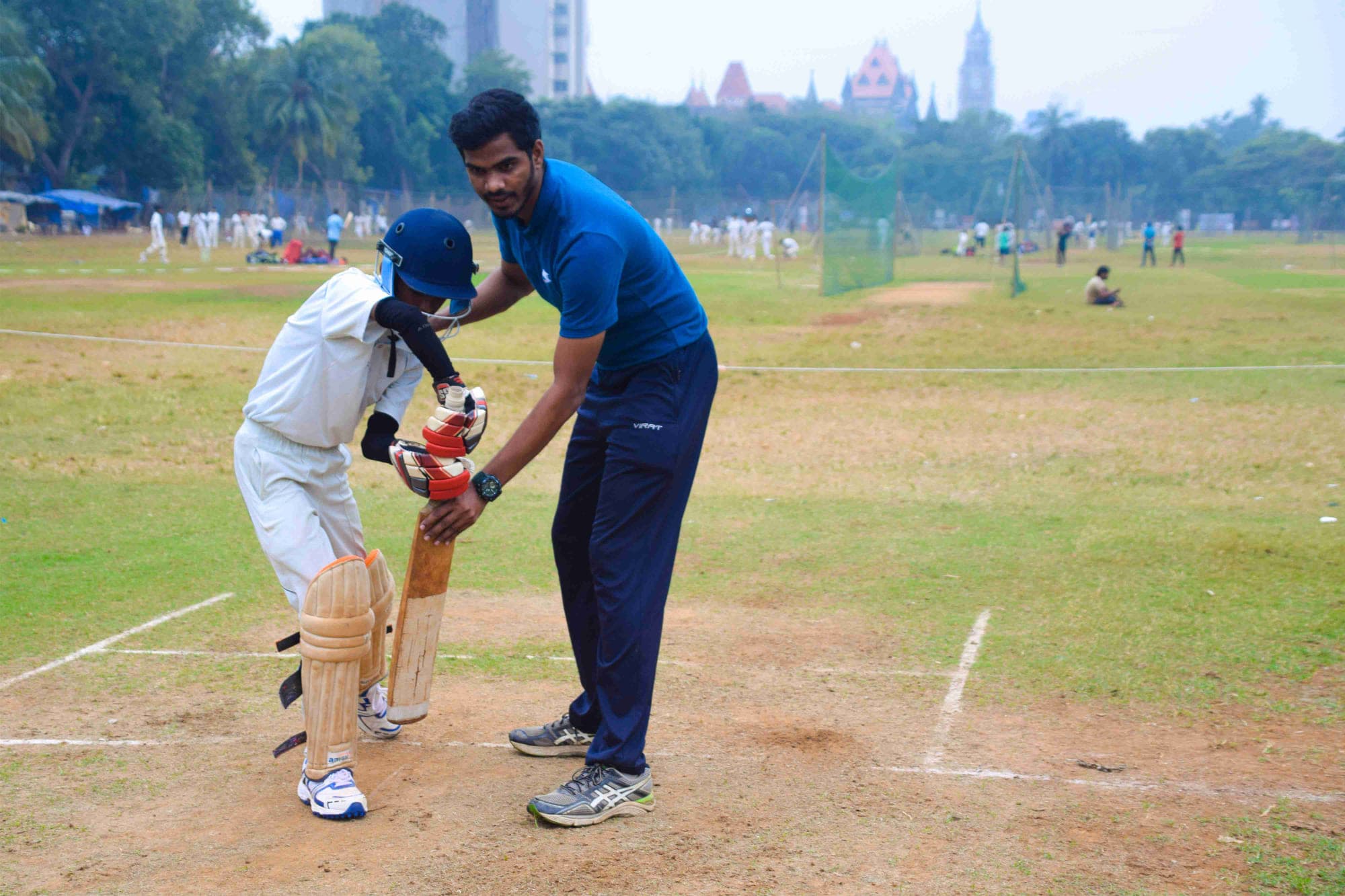 A coach setting a young batsman’s stance at the crease